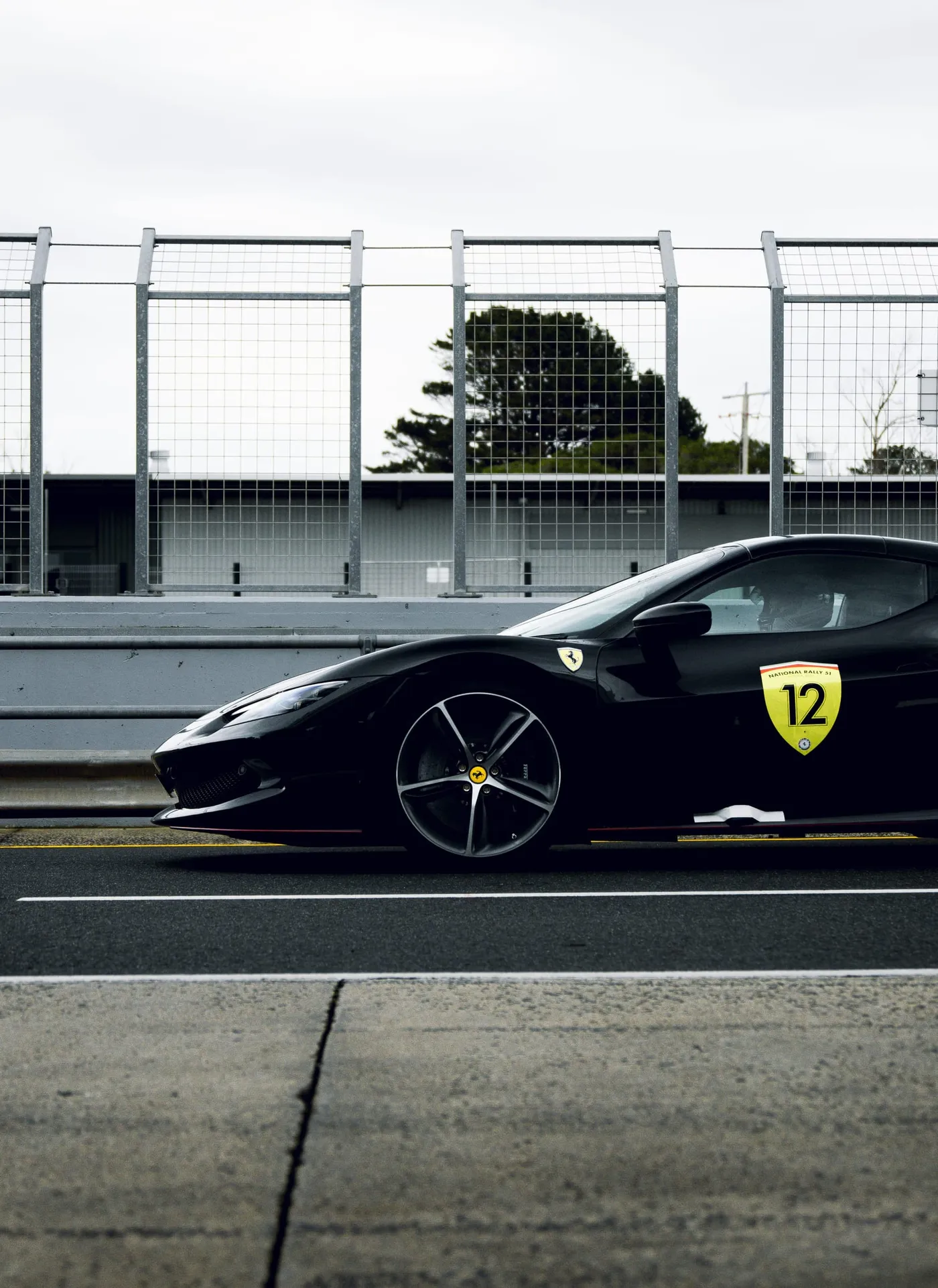 A black Ferrari carrying a number 12 rally plate on pit lane