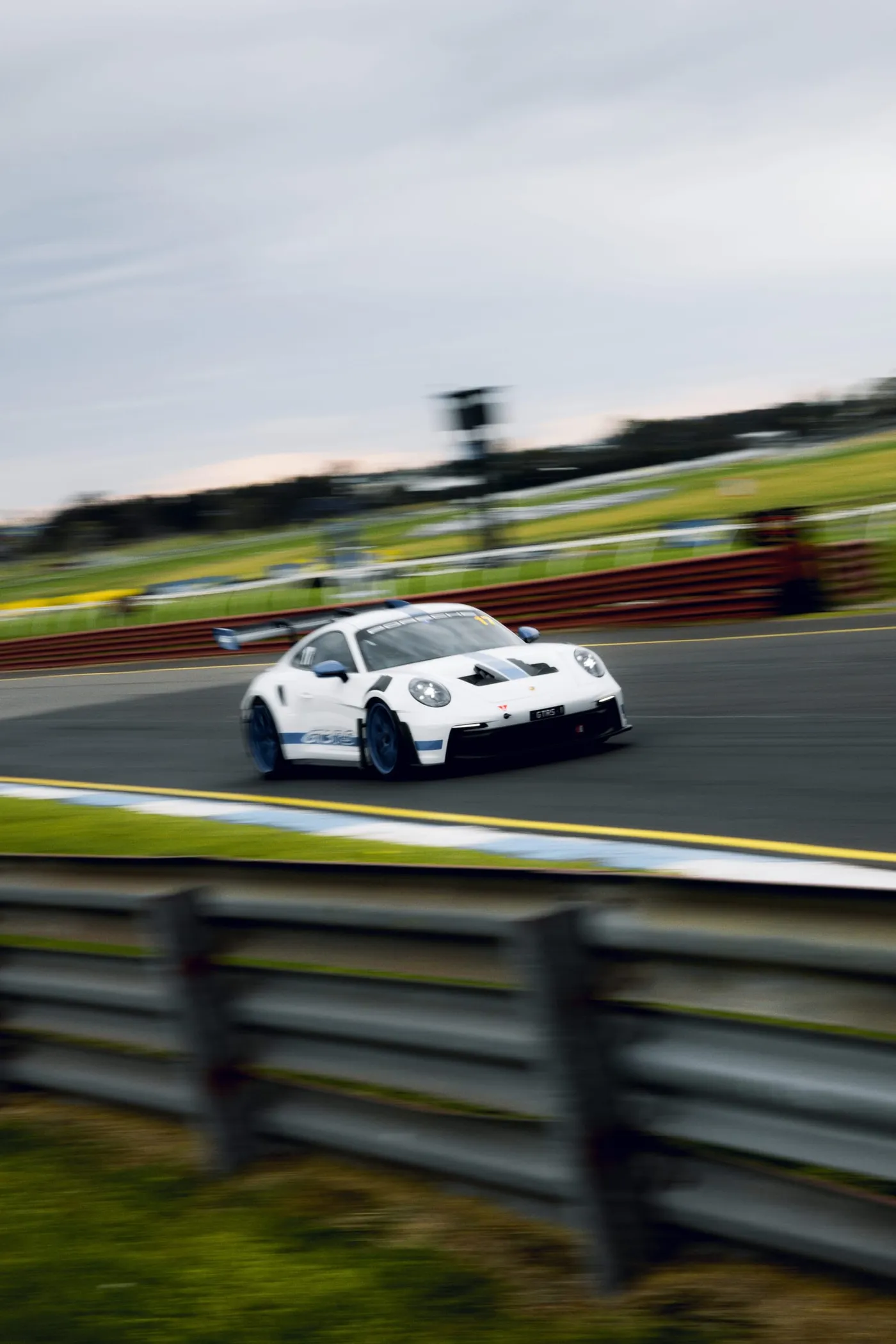 A white Porsche 911 GT3 RS panned through a corner on the circuit