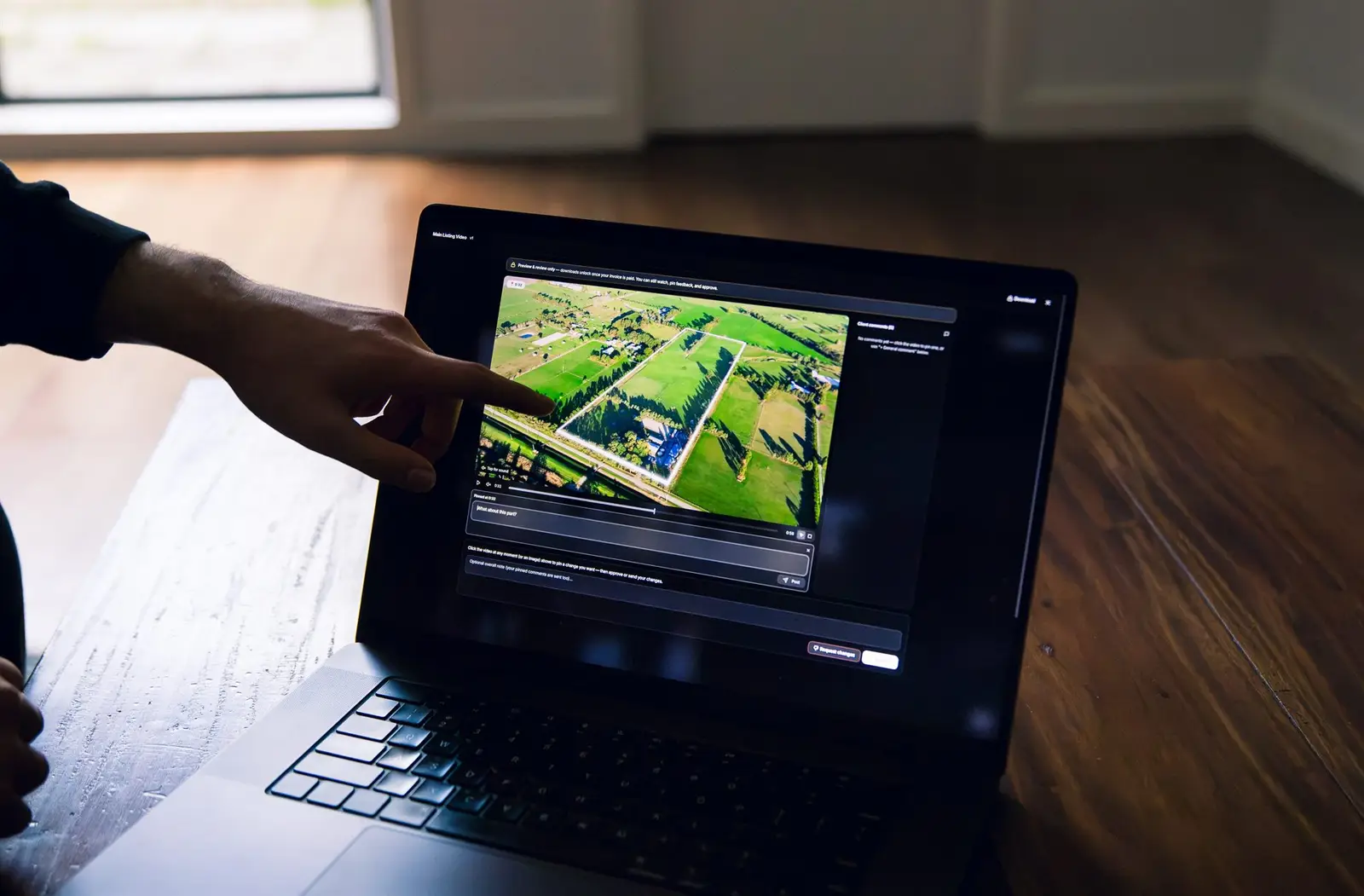 A hand pointing at a laptop screen showing finished work