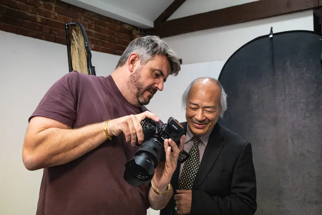 A photographer reviewing the shots on the back of a camera with his subject