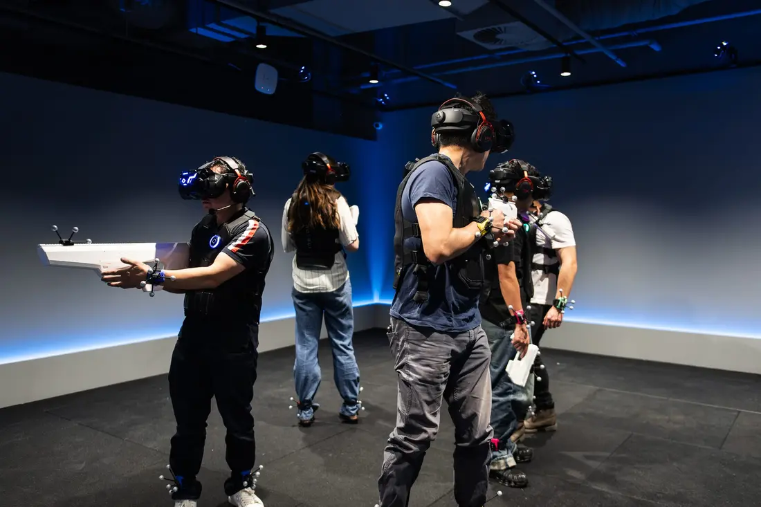 People in VR headsets and body gear in a Sandbox VR arena