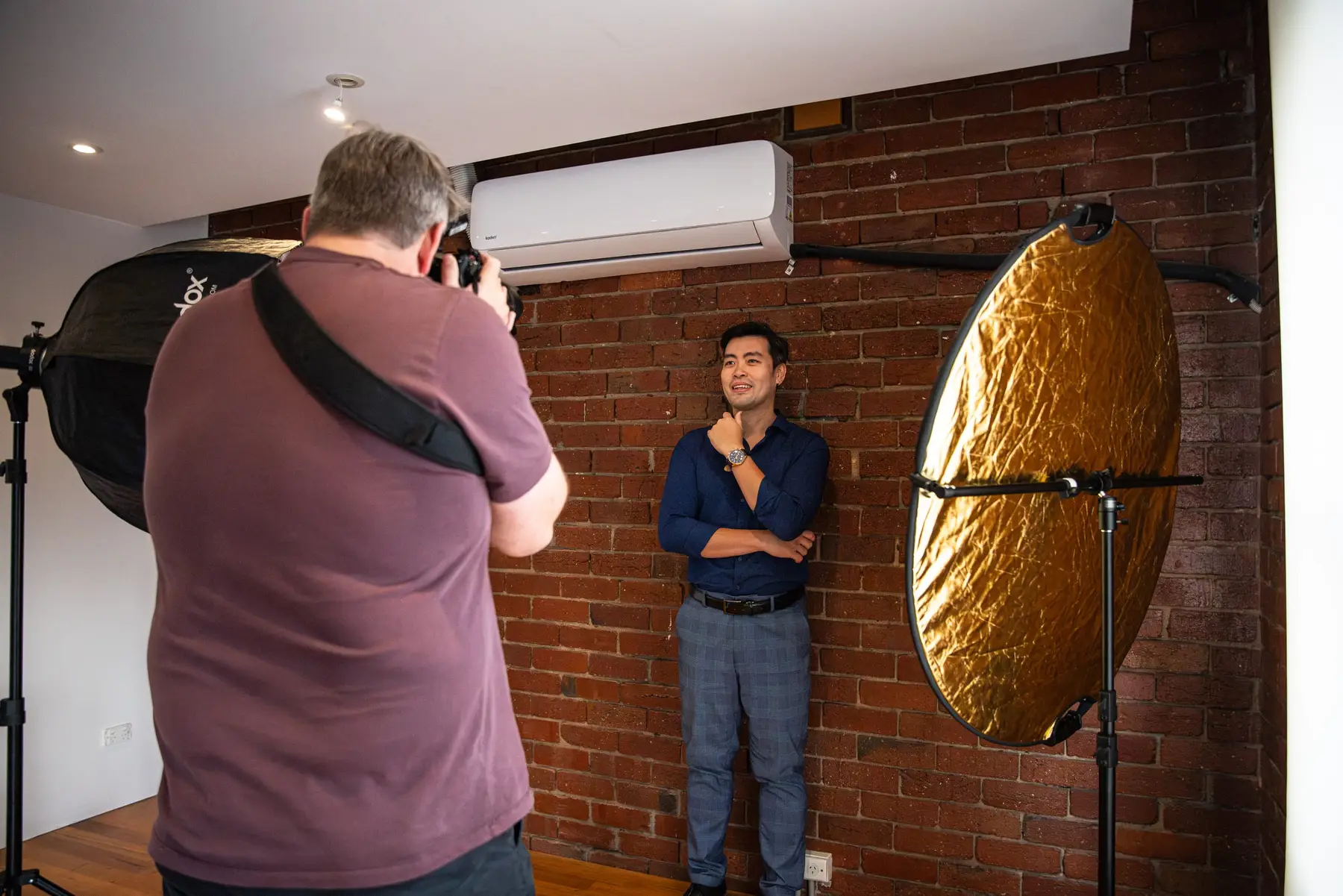 A photographer shooting a portrait in a brick-wall studio, cut for a 4:5 feed post