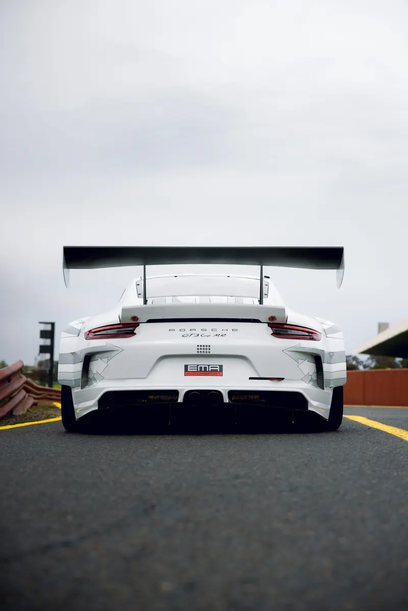 A white Porsche race car seen from behind on the track