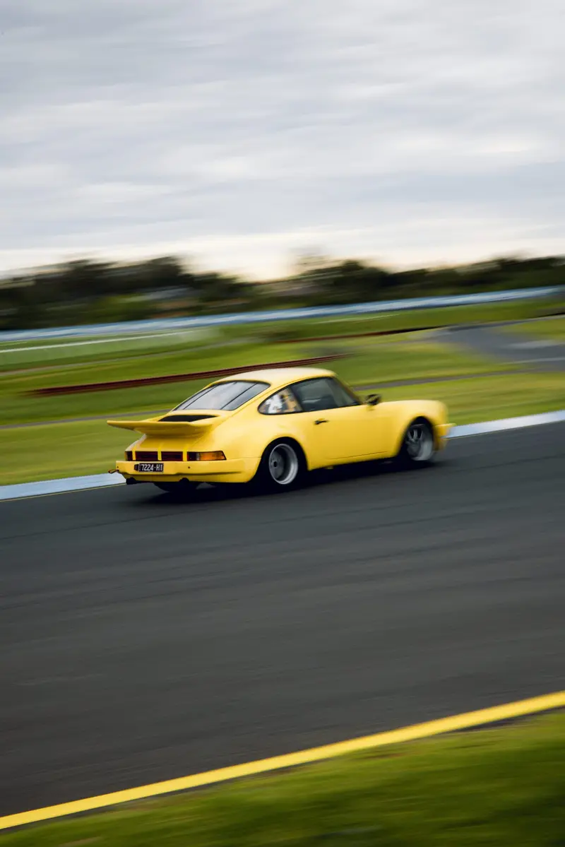 A yellow Porsche on the track, shot panning so the background streaks